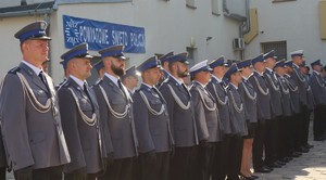 policjanci w  mundurze galowym stoją w  rzędzie w tle  napis Powiatowe Święto Policji