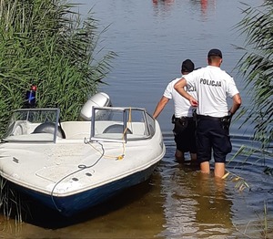 dwóch policjantów stoi koło łodzi