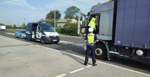 policjant i funkcjonariusz inspekcji transportu drogowego kontrolują ciężarówkę