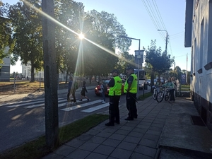 policjanci stoją przy przejściu dla pieszych, przez które  przechodzą dzieci