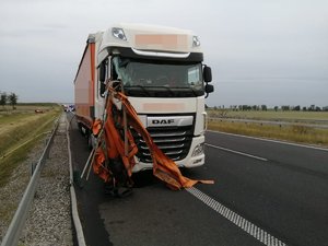 pojazd ciężarowy z uszkodzoną szybą czołową oraz elementem pomarańczowej plandeki