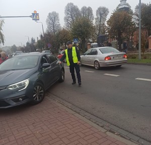 policjant  wskazuje  miejsce  gdzie  ma wjechać kierowca pojazdu  osobowego