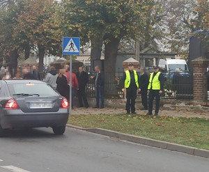 policjanci  stoją w  rejonie  cmentarza i  ruchliwej drogi