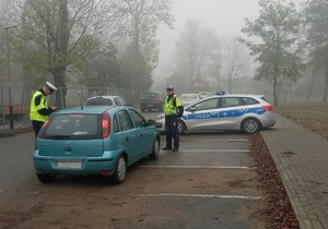 policjant kontroluje kierowcę pojazdu osobowego, drugi stoi obok pojazdu