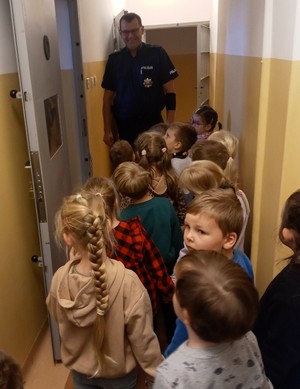 policjant  i dzieci znajdują się w korytarzu prowadzącym do policyjnych celi