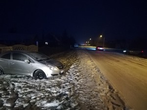 zaśnieżona droga, pojazd  osobowy, który  wypadł z  drogi  i uderzył w  ogrodzenie  posesji