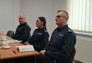 przy stole siedzi trzech umundurowanych policjantów, w tym jedna  kobieta