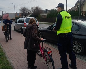 policjant  rozmawia z kobietami, które trzymają obok siebie rowery
