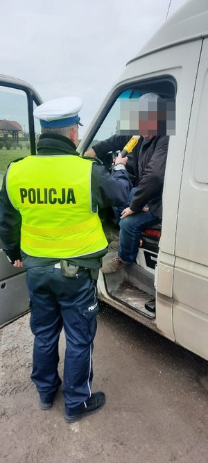 policjant ruchu drogowego bada trzeźwość kierowcy busa