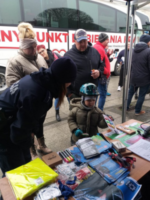 przed stoiskiem gromadzą się ludzie, w  tym mały chłopiec na rowerku