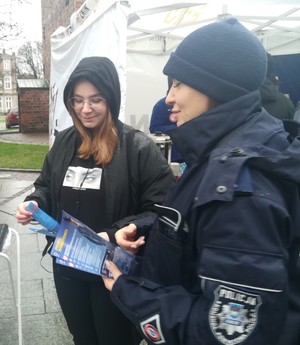 policjanta  wręcza ulotkę młodej dziewczynie