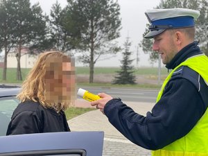 policjant  ruchu drogowego bada stan trzeźwości kierujące pojazdem osobowym