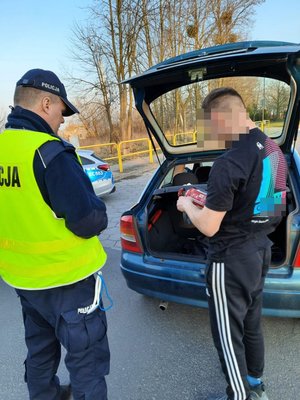 policjant sprawdza przewożony ładunek w  pojeździe, obok niego stoi młody chłopak