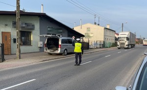 policjant  daje sygnał do zatrzymania się kierującemu ciężarówką