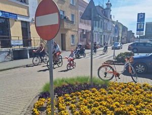 rowerzyści przejeżdżają przez skrzyżowanie, za nimi jedzie radiowóz