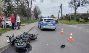 na jezdni leży uszkodzony  motorower, za min stoi radiowóz policyjny, a obok  niego osoby postronne