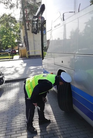 policjant  kontroluje  ogumienie autokaru