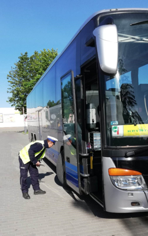 policjant  sprawdza stan ogumienia autokaru