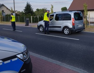 policjant sprawdza stan trzeźwości kierowcy samochodu koloru srebrnego