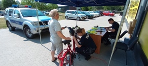 policjantka znakuje  rower, który trzyma  mężczyzna, policjant  wypełnia  dokumentację