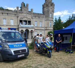 policyjny namiot, radiowóz oraz motocykl i policjanci  na  festynie