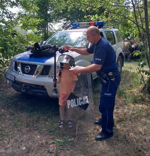 policjant  pomaga założyć strój policyjny dziecku