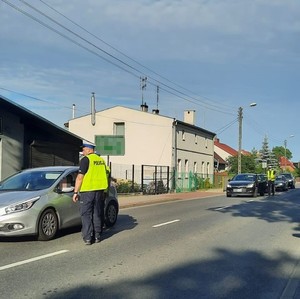 policjant  sprawdza trzeźwość  kierowcy srebrnej osobówki