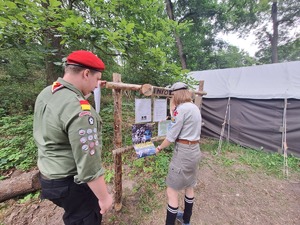 harcerze przypinają plakat do tablicy ogłoszeń