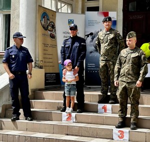 policjanci, wojskowi  oraz dziecko stoją na schodach