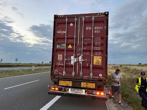 Tył pojazdu ciężarowego. Z lewej strony widoczne pasy ruchu drogi ekspresowej S5. Z prawej strony idzie policjantka i kierujący ciężarówką.