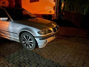 Przód pojazdu marki BMW, który brał udział w zdarzeniu drogowym. Za nim budynek.