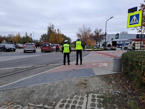 Policjanci ruchu drogowego obserwują jak przemieszczają sie piesi i pojazdy w obrębie cmentarza.