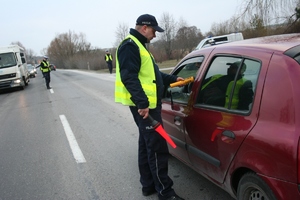 Policjant sprawdza stan trzeźwości kierującego siedzącego za kierownicą samochodu osobowego.