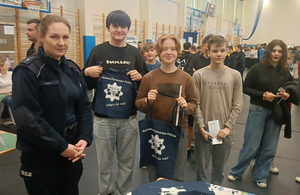 umundurowana  policjantka stoi obok czterech chłopców