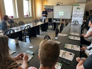 policjantka prowadzi prelekcje, słuchacze siedzą przy stolach