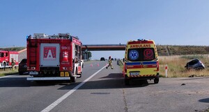 karetka pogotowia ratunkowego oraz wóz strażacki stoją na pasie ruchu, w przydrożnym rowie znajduje się samochód Nissan