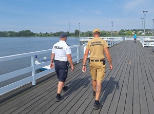 policjant  i strażak idą pomostem