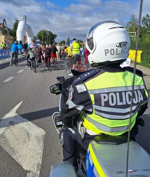 policjant  na  motocyklu a przed nim rowerzyści