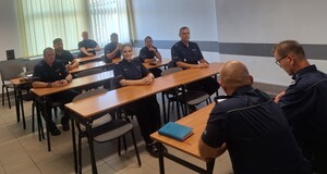 policjanci znajdują się w sali, zasiedli w  ławkach