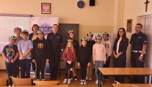 przy tablicy stoją dzieci, kobiety oraz policjanci