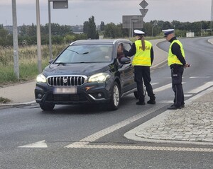dwóch policjantów stoi obok auta